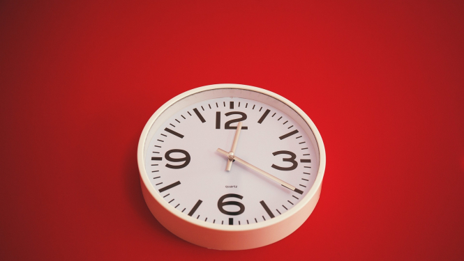 Balts sienas pulkstenis uz sarkana fona