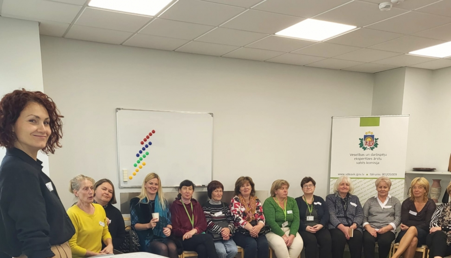 zāle, darbinieki sēž, klausās, lektore stāv, stāsta, projektors